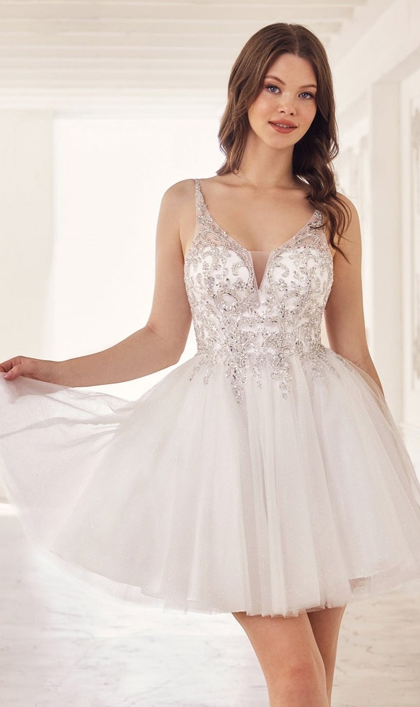 A woman in the Lace-Up Short A-Line Homecoming Dress CY022 with sparkling embellishments and a beaded bodice stands indoors, holding the sides of her skirt.